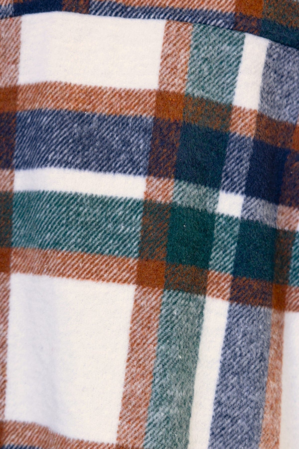 Close-up of Braedyn Shacket fabric featuring a soft plaid design in navy, green, orange, and cream colors.