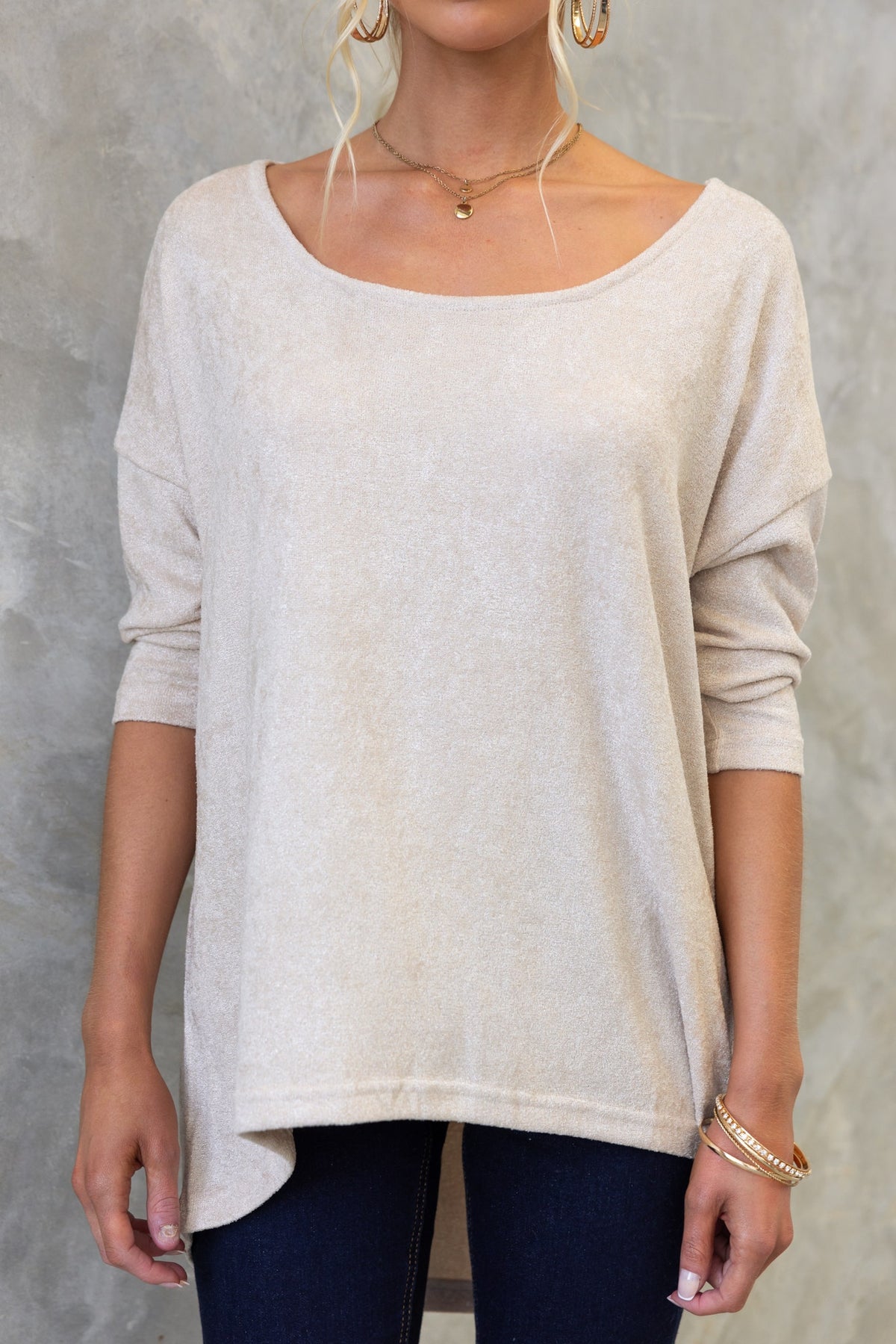Model showcasing the Vargo Top with boat neckline and high-low hemline in light beige color.