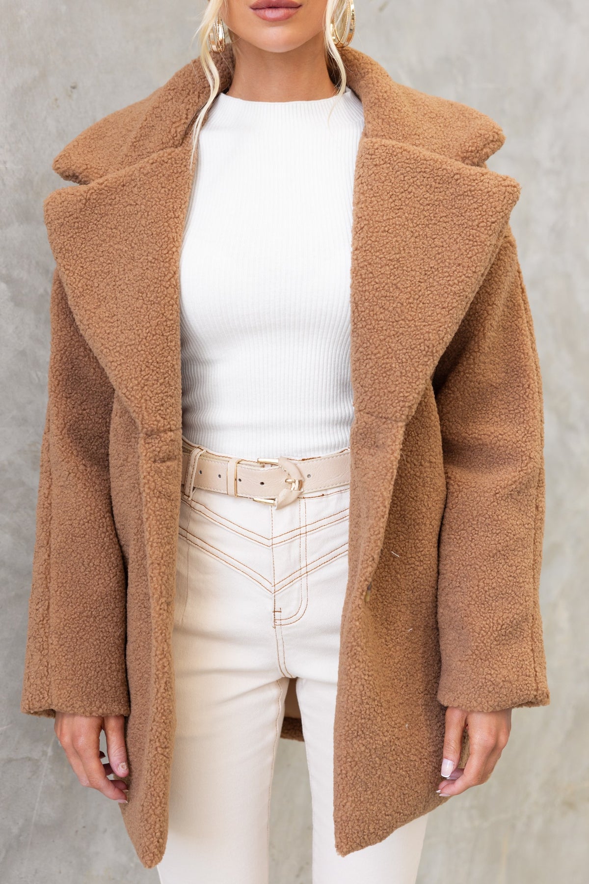 Stylish Phala Coat in teddy material with collar, lapel, and front pockets, worn over a white top and beige pants.