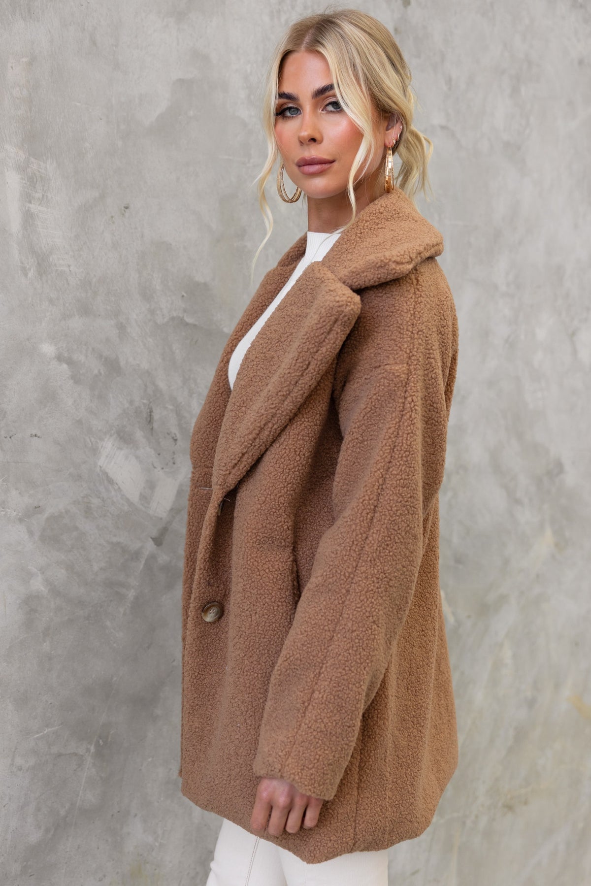 Side view of a woman wearing a cozy Phala Coat in teddy fabric, featuring a lapel collar and button front.