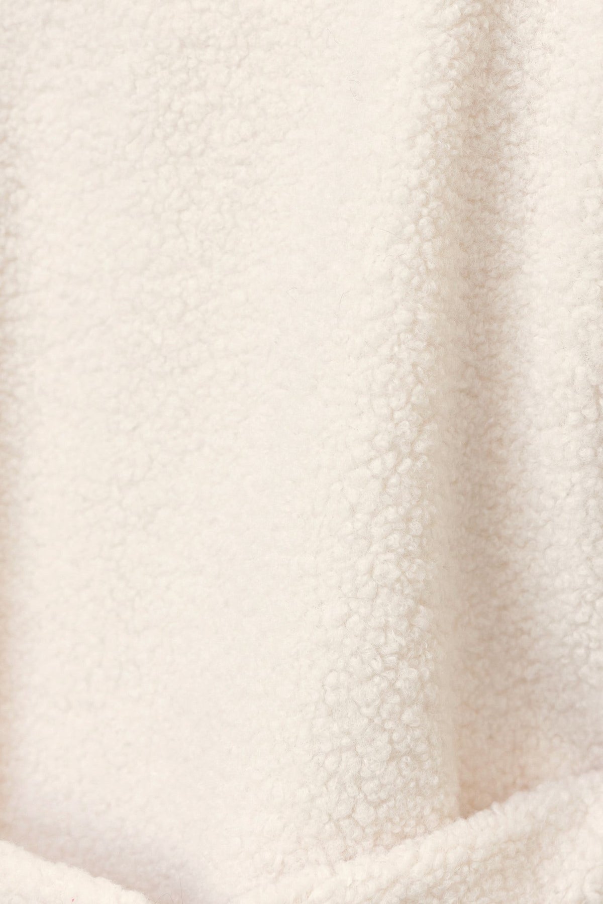 Textured teddy fabric in soft cream color, perfect for cozy winter outfits or loungewear.