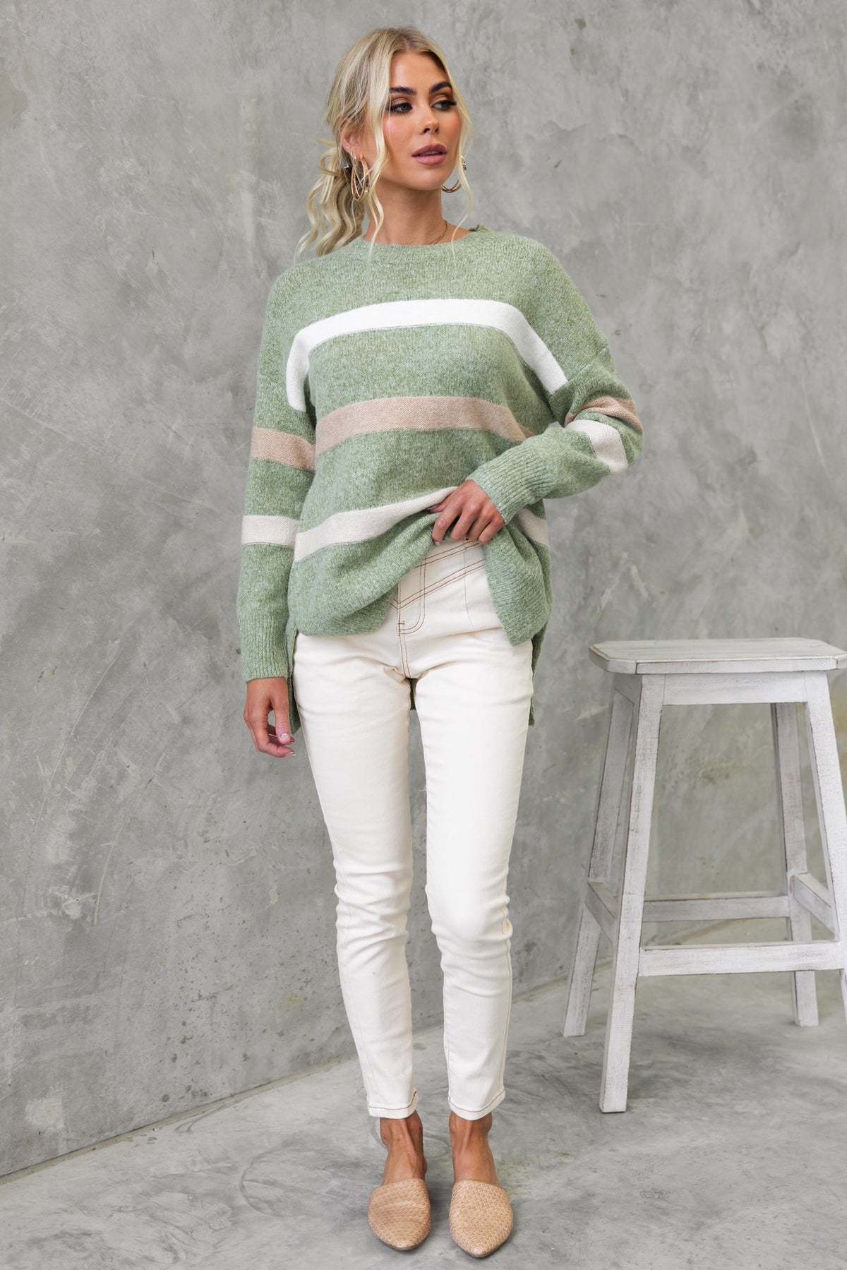 Model wearing Lukki Jumper with green and white stripes, high-low hem, paired with white jeans and beige flats.