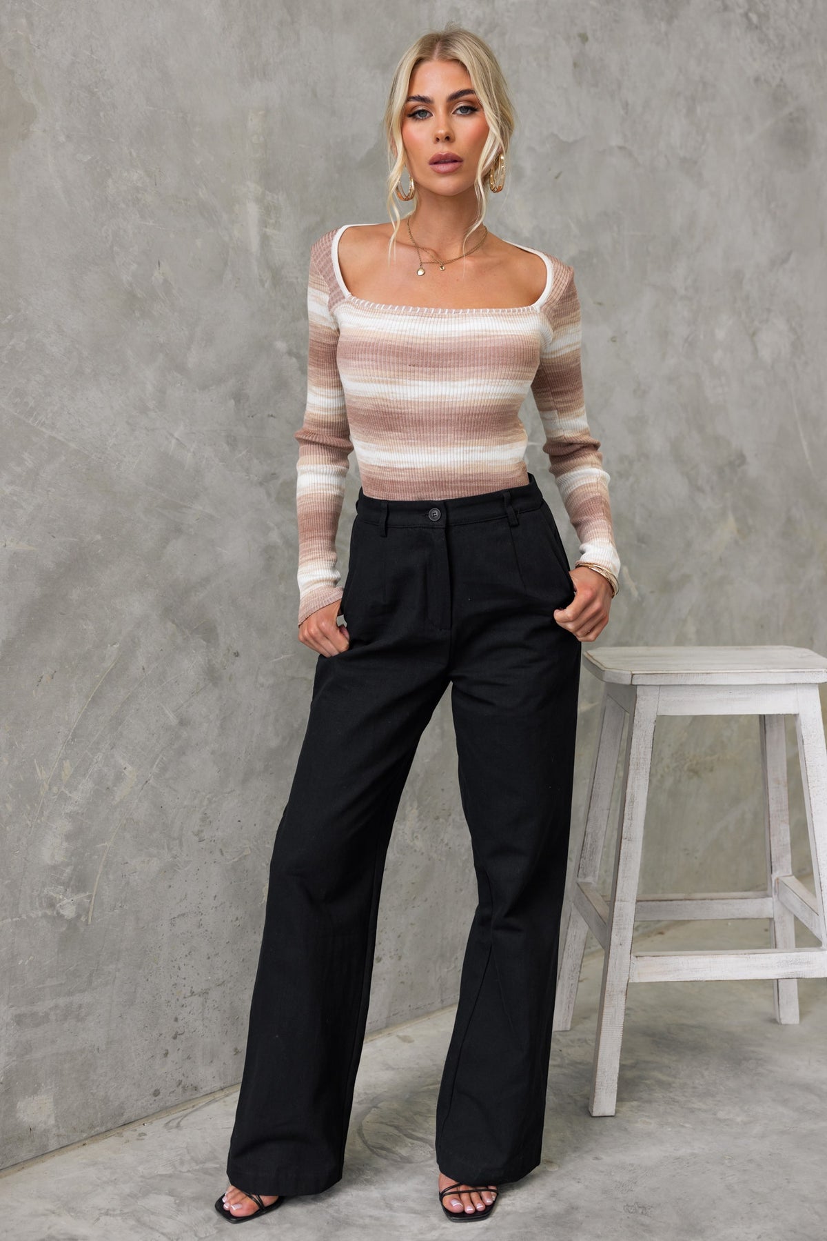 Yitra Top with square neckline in ribbed knit, paired with black wide-leg trousers, model posed in modern setting.