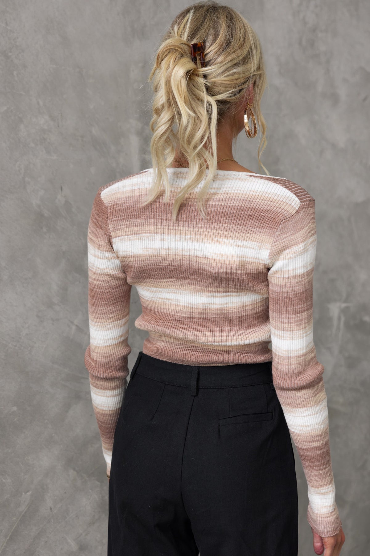 Back view of Yitra Top featuring a square neckline and ribbed knit material in pastel stripes, styled with black pants.