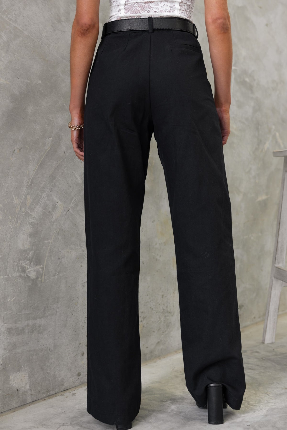 Back view of Rayden Denim Pants in black with wide legs, mid-high waist fit, and belt detail.