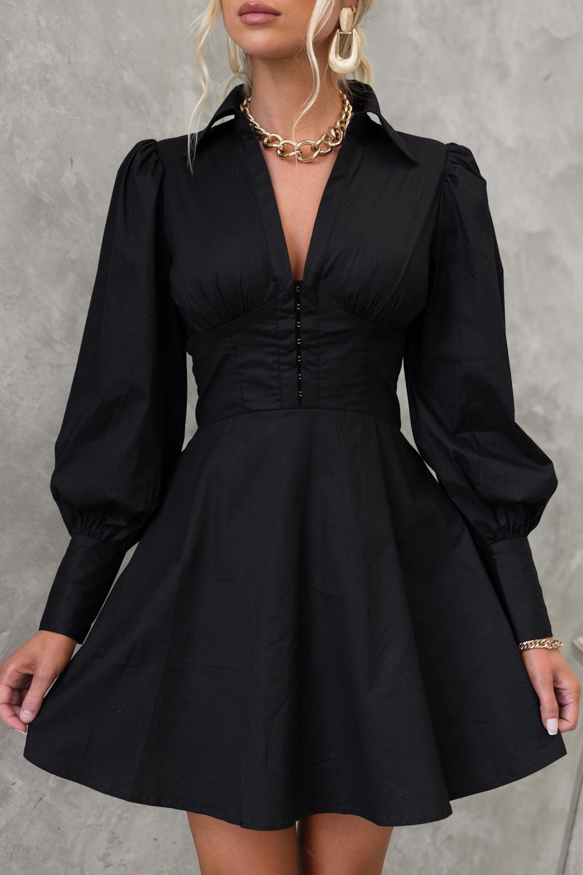 Elegant black Ematie dress with a V-neckline, puff sleeves, and a fitted waist, perfect for any occasion.
