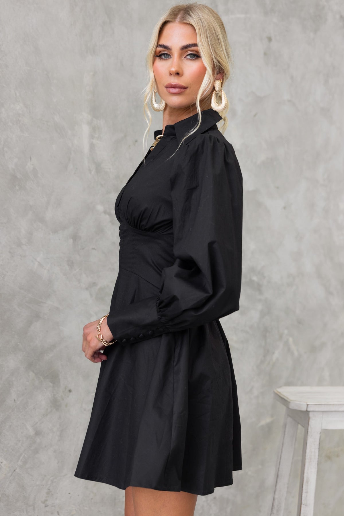 Side view of model wearing the Ematie black dress with V-neckline and puff sleeves, styled elegantly for a chic look.
