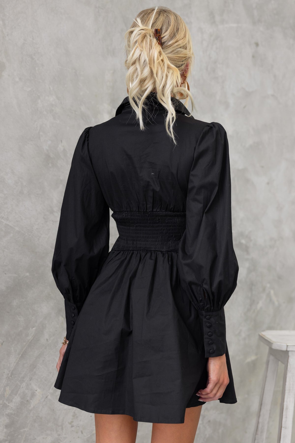 Back view of the Ematie Black Dress with a collar, V-neckline, and puff sleeves. Elegant and fitted design.