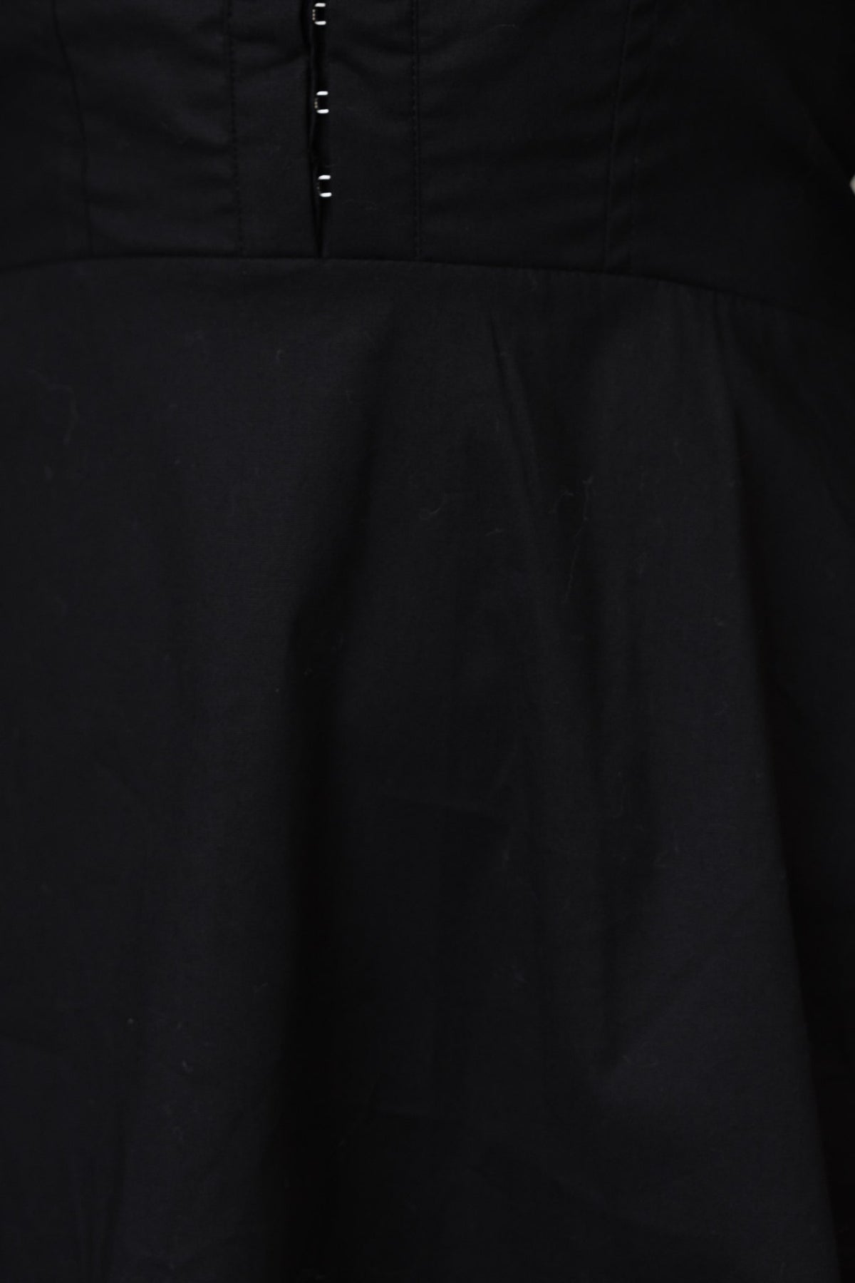 Close-up of Ematie black dress featuring V-neckline and hook & eye fastenings.