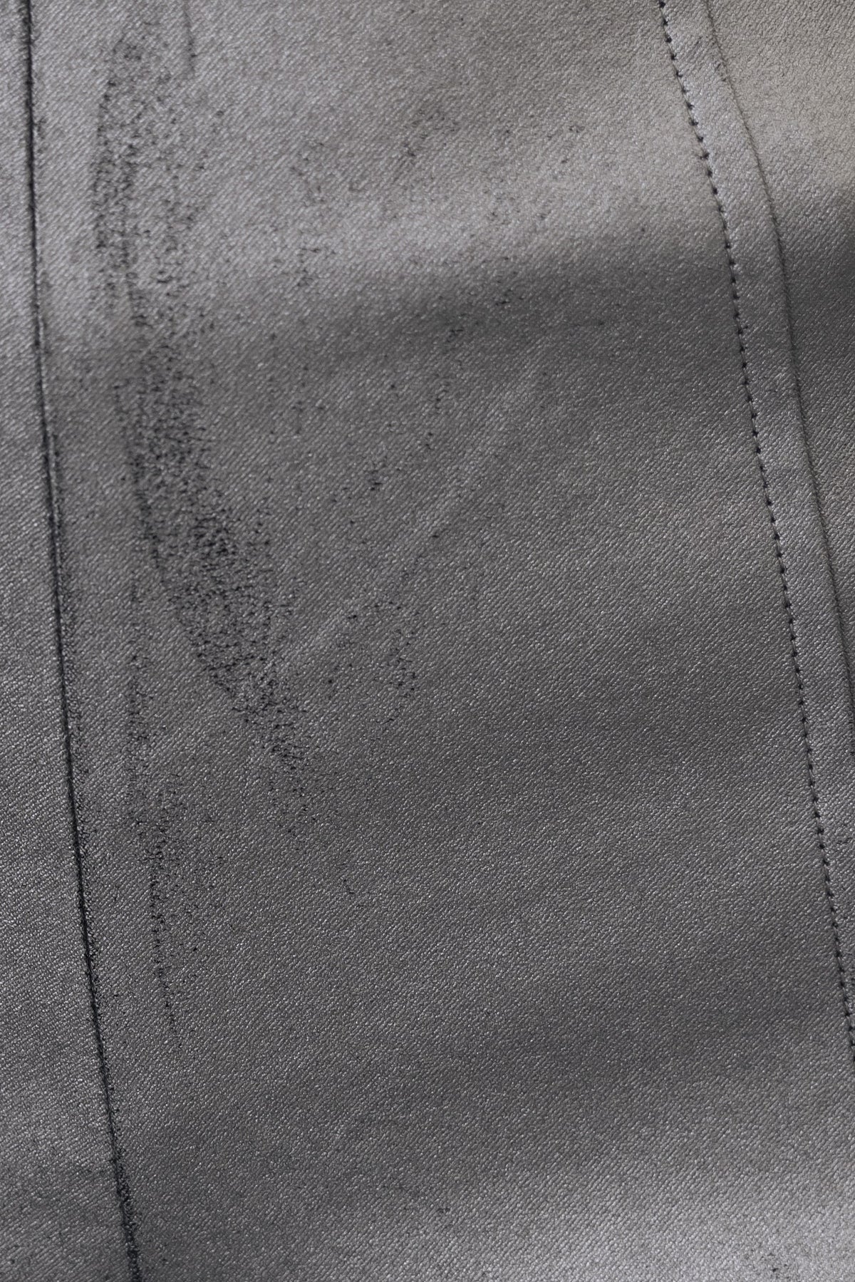 Close-up of the texture of faux leather fabric in a metallic finish, featuring subtle creases and stitching details.