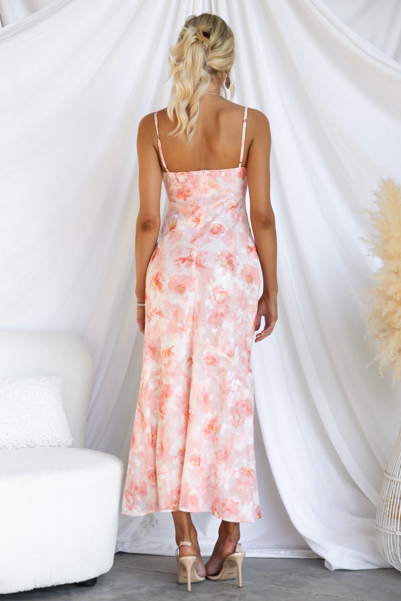 Back view of a woman wearing a pink floral Beaming Maxi Dress with adjustable straps and a split at the front.
