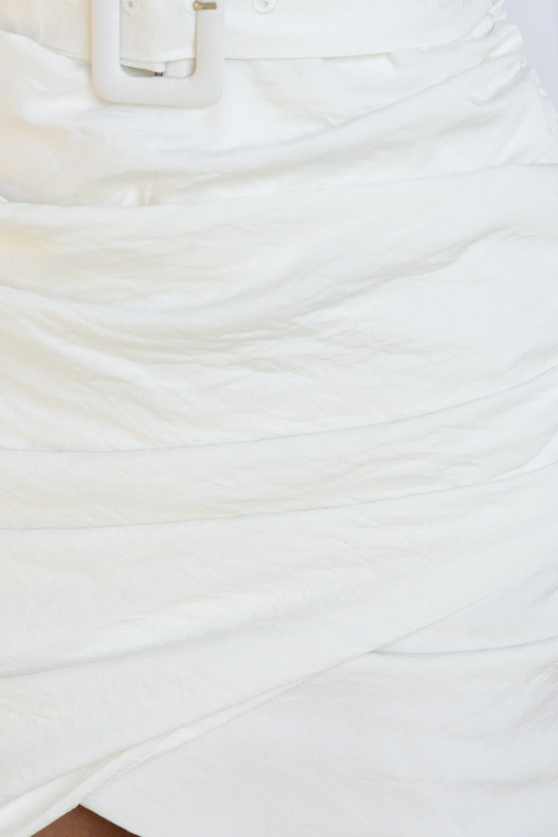 Close-up of the ashwood dress showcasing the white fabric, ruched details, and removable belt buckle.