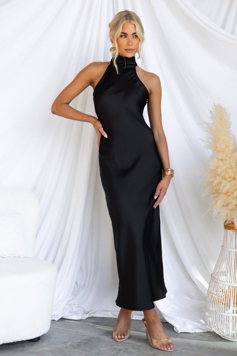 Model wearing a black satin Humble Maxi Dress with a high tie neckline on a white backdrop.