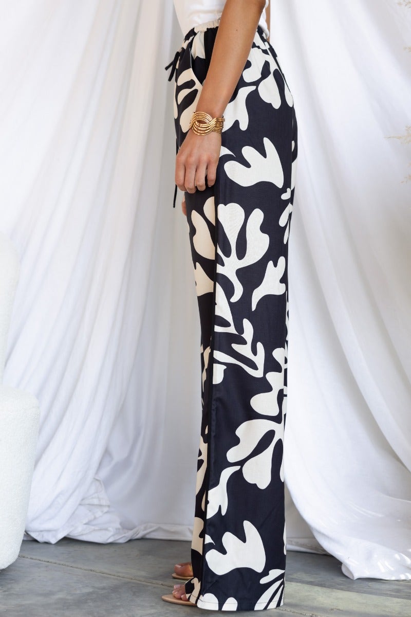 Side view of White Lies Pants featuring a black and white floral print, elastic waistband, and drawstring tie.