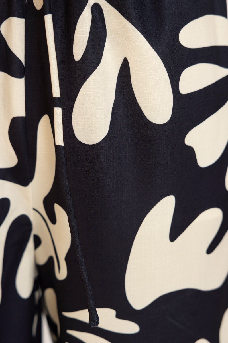 Close-up of a black and cream patterned top featuring abstract floral designs and adjustable tie halter neckline.