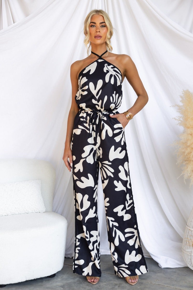 Model wearing White Lies Pants with black based print and elastic waistband, stylishly posed against a backdrop.