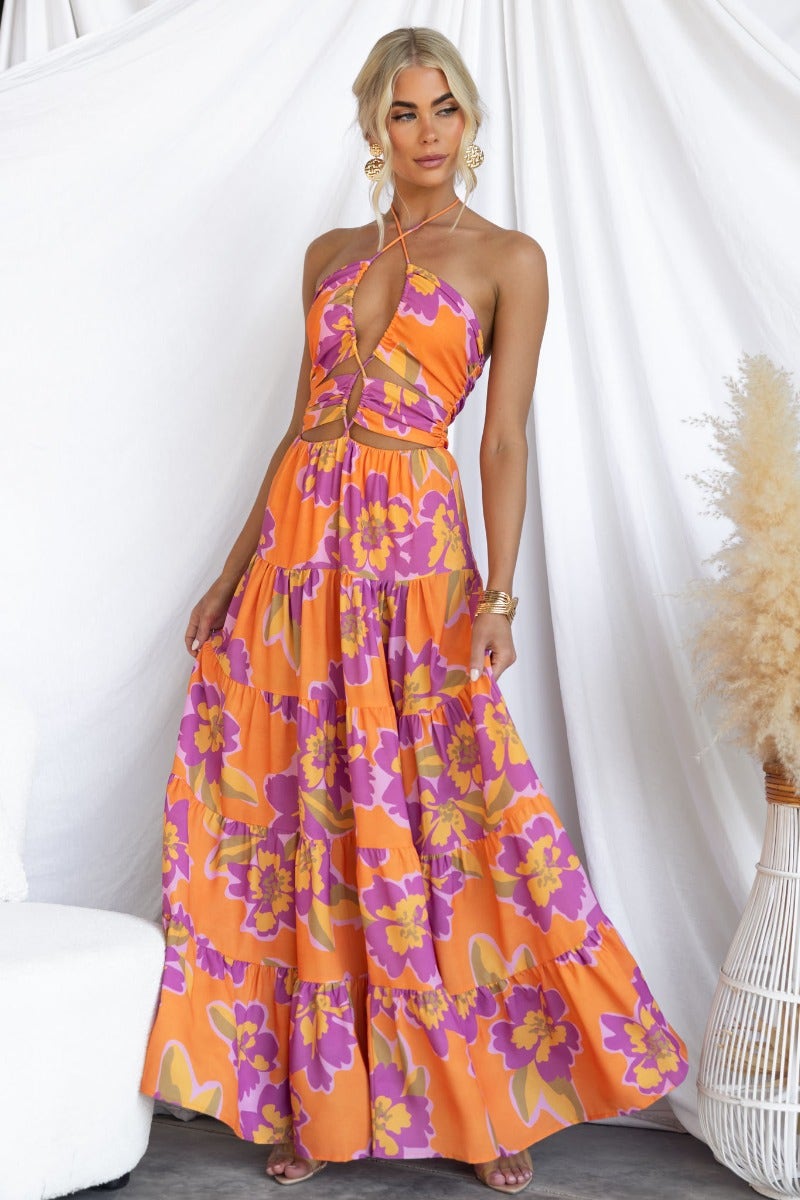 Over Joyed floral print maxi dress with adjustable halter neckline and cut-outs, styled in vibrant orange and pink colors.