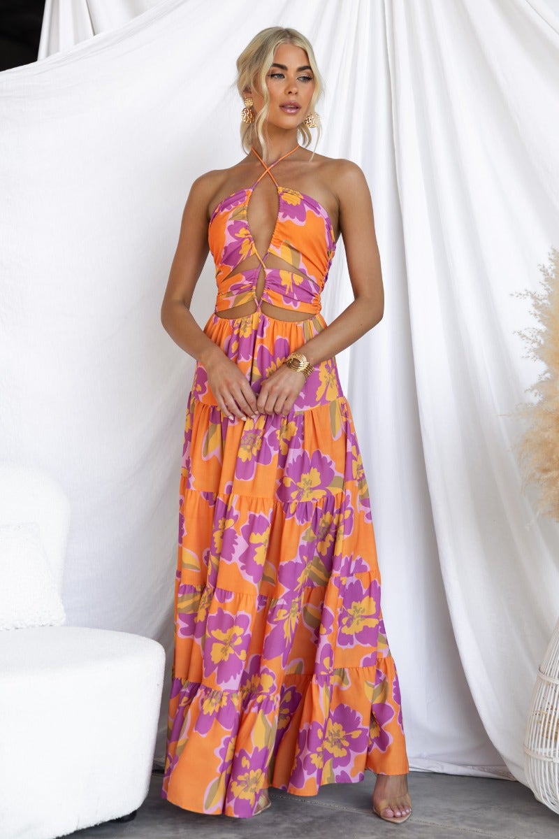 Over Joyed maxi dress featuring adjustable tie halter neckline and vibrant floral print, styled by model in chic setting.