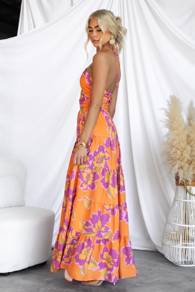 Model wearing Over Joyed Maxi Dress with floral print and adjustable halter neckline, styled in a modern setting.