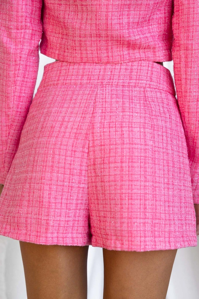 Back view of vibrant pink tweed shorts featuring a side zip and lined design.