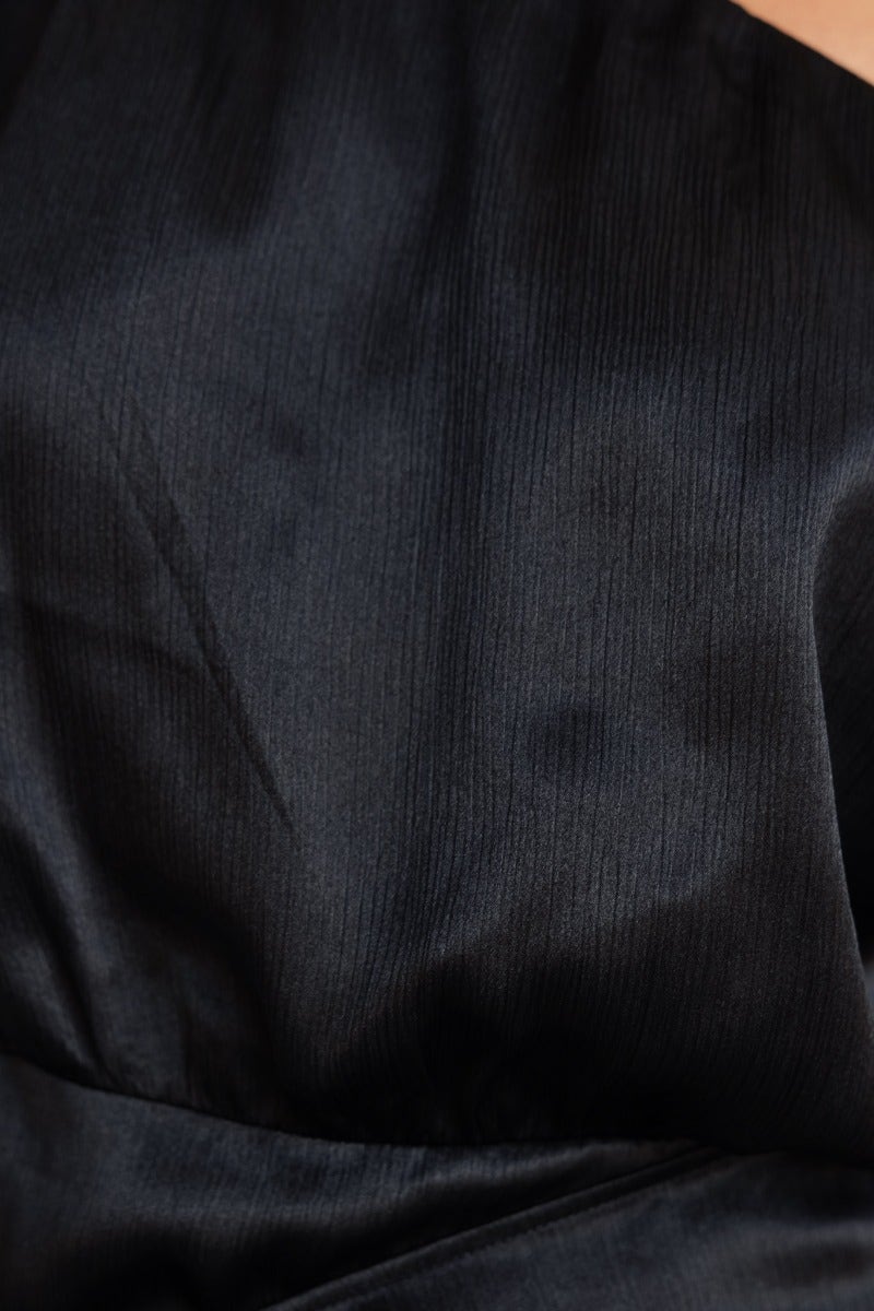 Close-up of the textured black satin fabric of the Dazzling Dress, highlighting its elegant sheen and smooth finish.