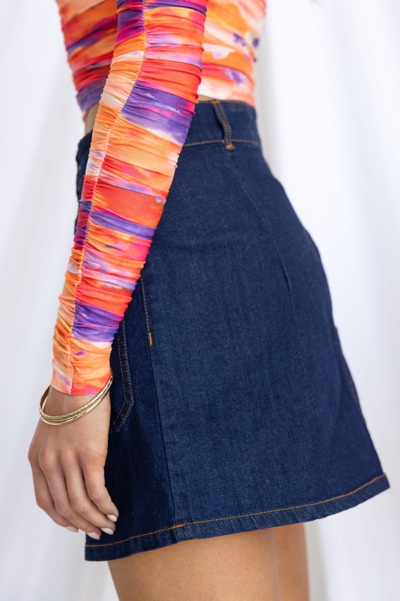 Side view of a mid-low waist denim skirt paired with a colorful long-sleeve top, showcasing stylish pockets.