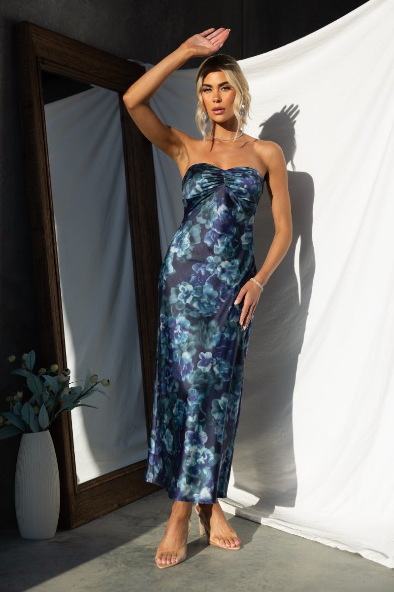 Model wearing Yuna maxi dress, navy floral print, strapless design, showcasing elegant style.