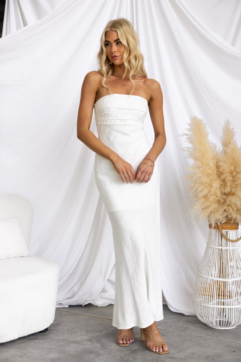 Model wearing the Wilder Maxi Dress, a strapless linen blend maxi dress in white with a fitted bust and flowing silhouette.