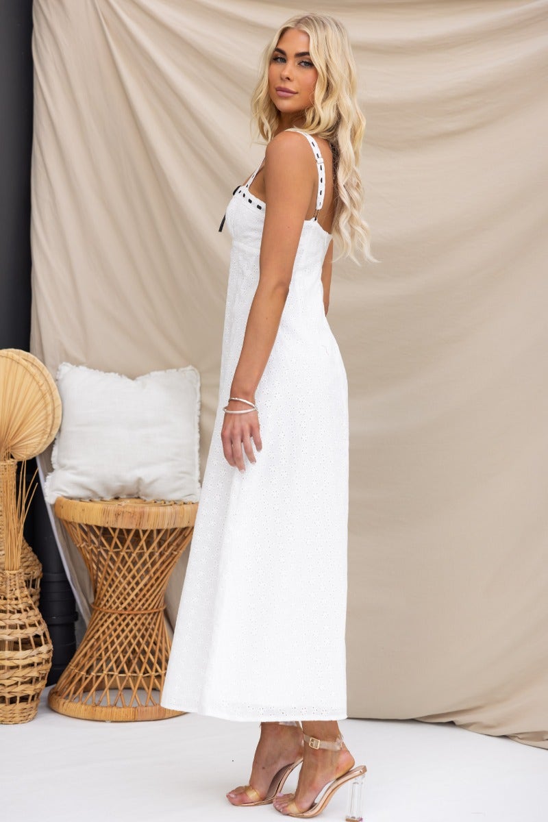 Side view of a model in a Cottage Dreams Maxi Dress featuring adjustable straps and ribbon detailing, styled with elegant accessories.