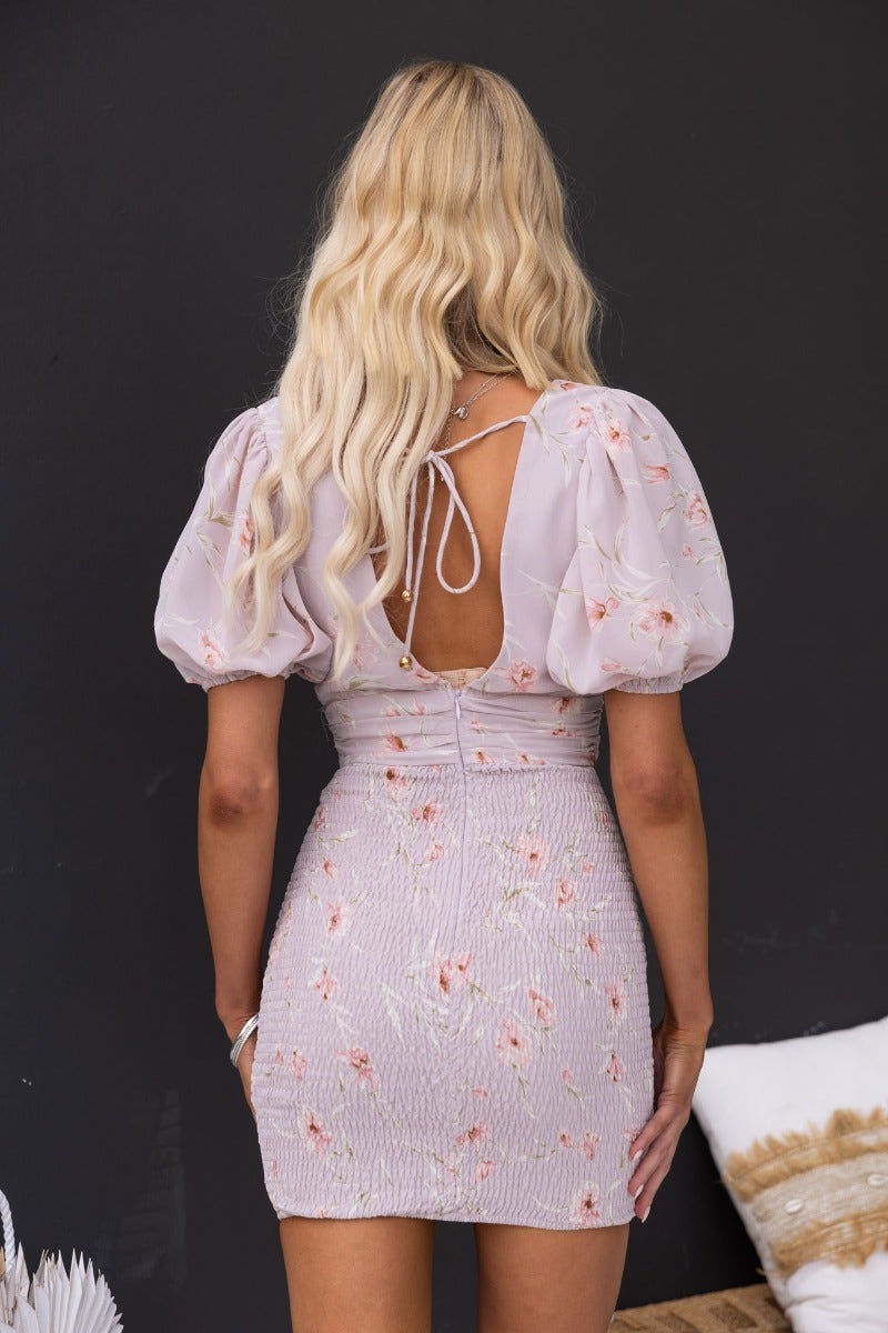 Back view of Oriel Dress featuring floral print, V-neckline, and puffed sleeves with tie detail.