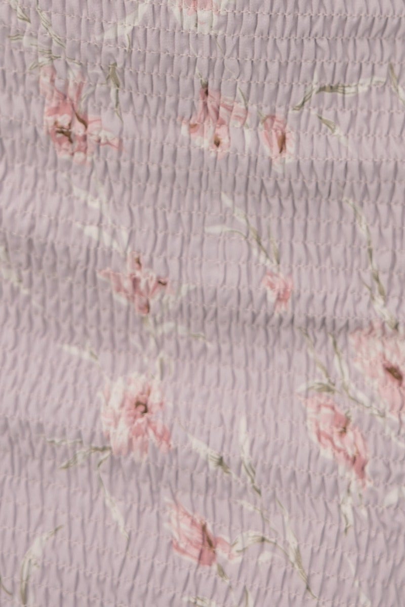 Close-up of floral print fabric featuring delicate pink flowers on a textured lavender background.