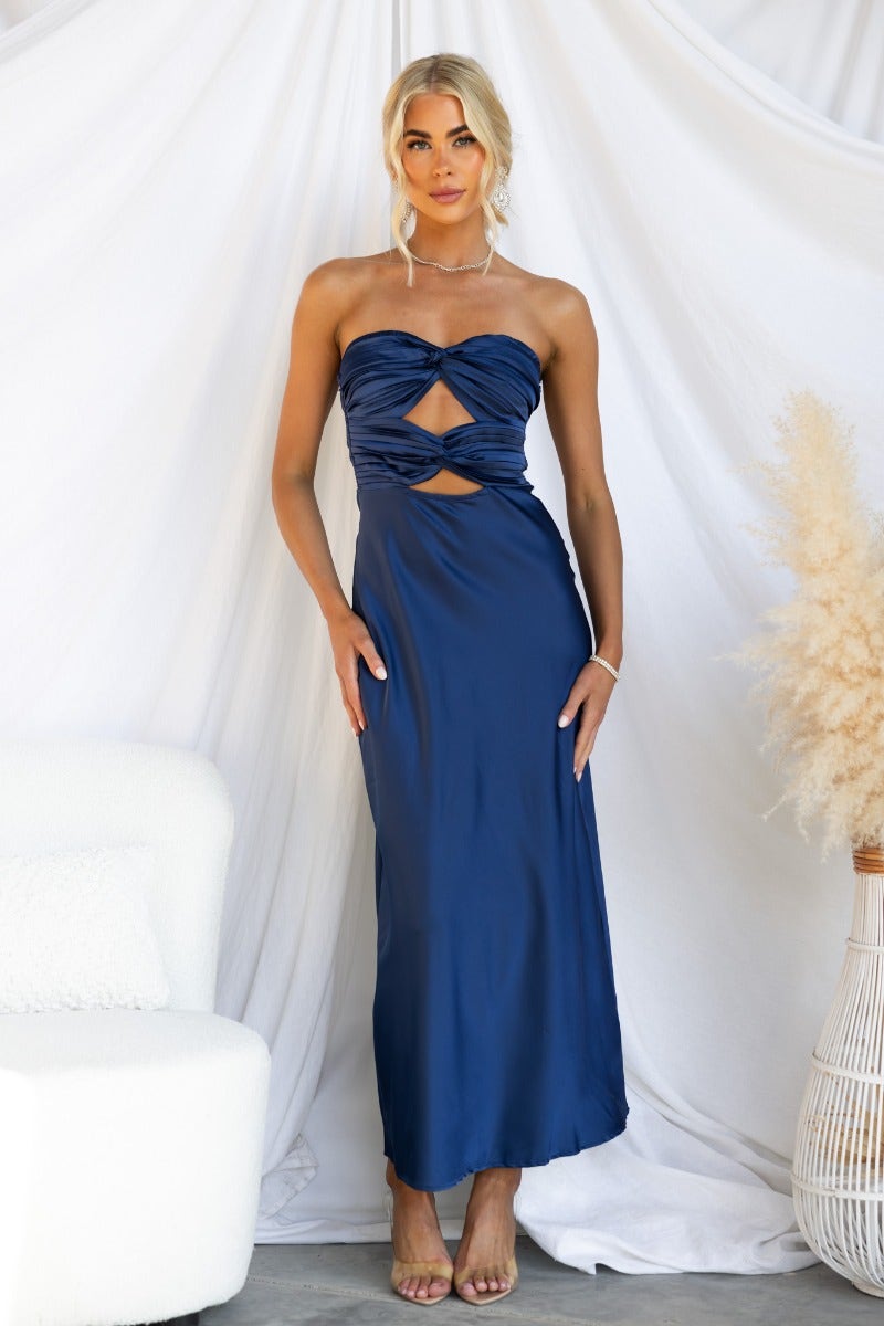 Model wearing a navy Zadora maxi dress with a strapless and cut-out design, styled against a soft backdrop.