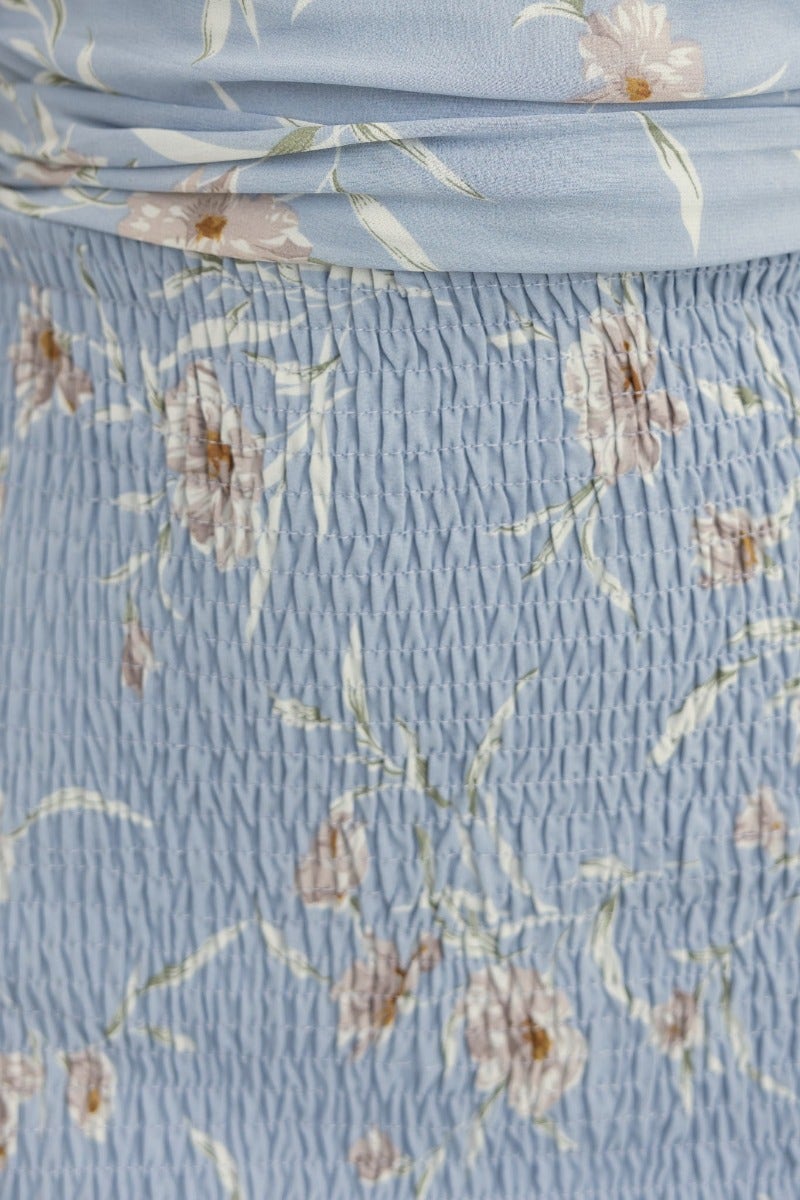 Close-up of Oriel dress featuring soft blue floral print and smocked texture, showcasing its elegant design.