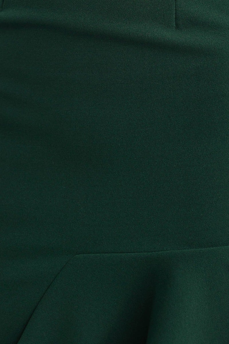 Close-up of green crepe fabric showcasing the texture and asymmetrical hemline of the midi dress.