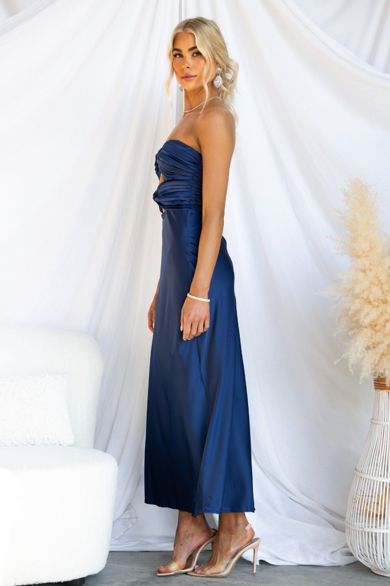 Side view of Zadora Navy Maxi Dress, strapless with cut-out and zip back, styled with heels.