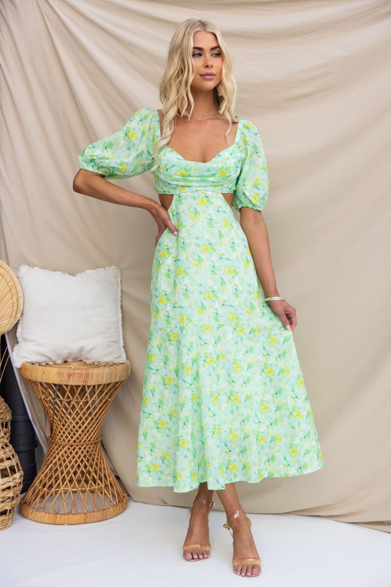 Zesty midi dress with floral print, elastic sleeves, cut-out waist, and padded bust, styled on a model.