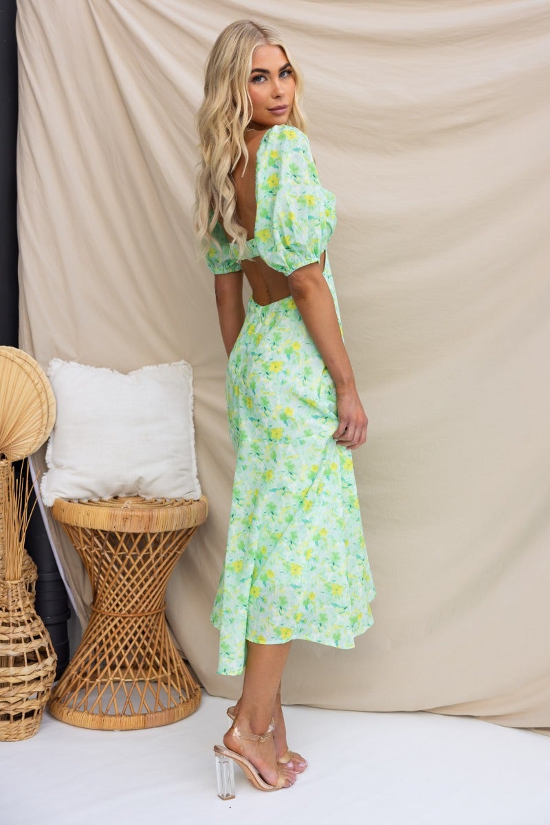 Model in a floral print Zesty Midi Dress with elastic sleeves and back cut-out, showcasing a stylish summer look.