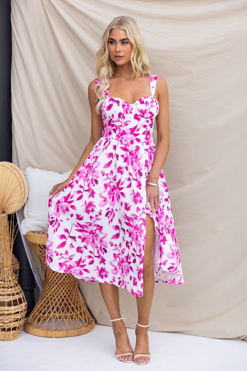 Model wearing a floral print Quiet Days midi dress with adjustable straps and a front split.