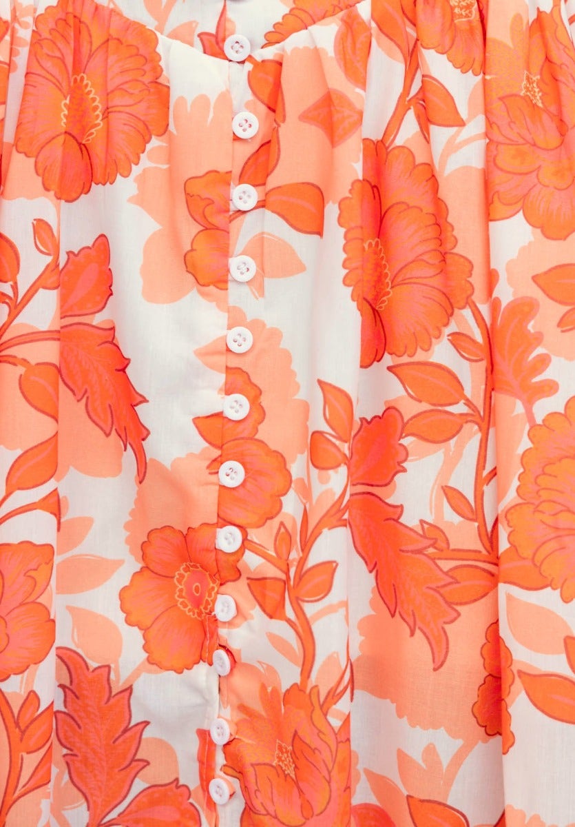 Close-up of floral print fabric in orange hues with functional buttons on the Idella Maxi Skirt.