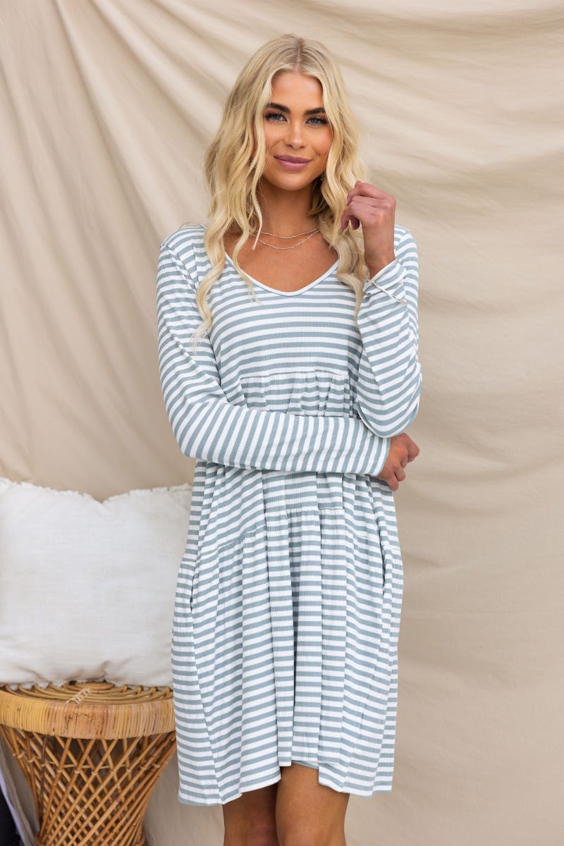 Sorrell Dress in ribbed blue and white stripes, featuring a V-neckline and pockets, modeled by a woman.