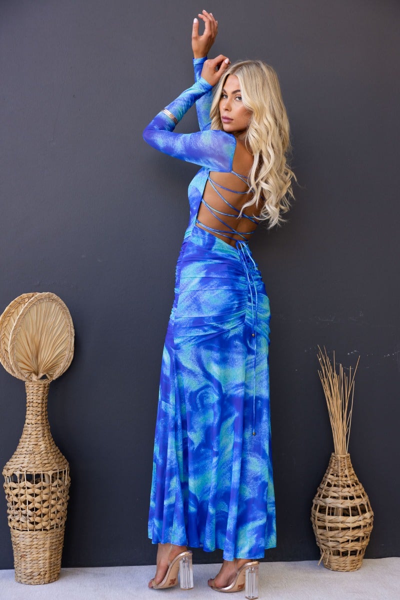 Model wearing a blue and green Keziah Maxi Dress with cross-over tie detail, showcasing a high split and ruched waist.