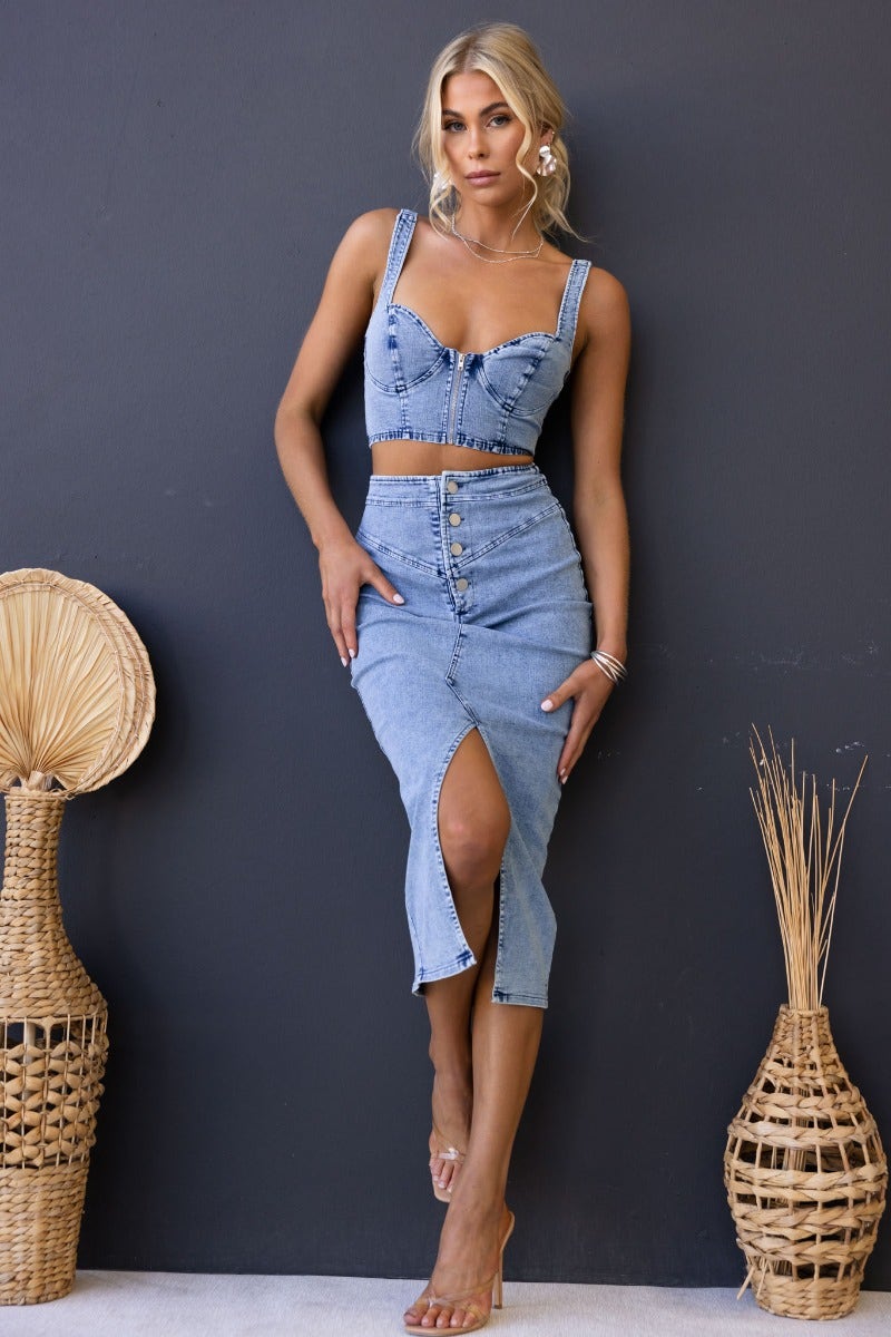 Model wearing Genevieve denim midi skirt with button-up front and high split, styled with matching crop top.