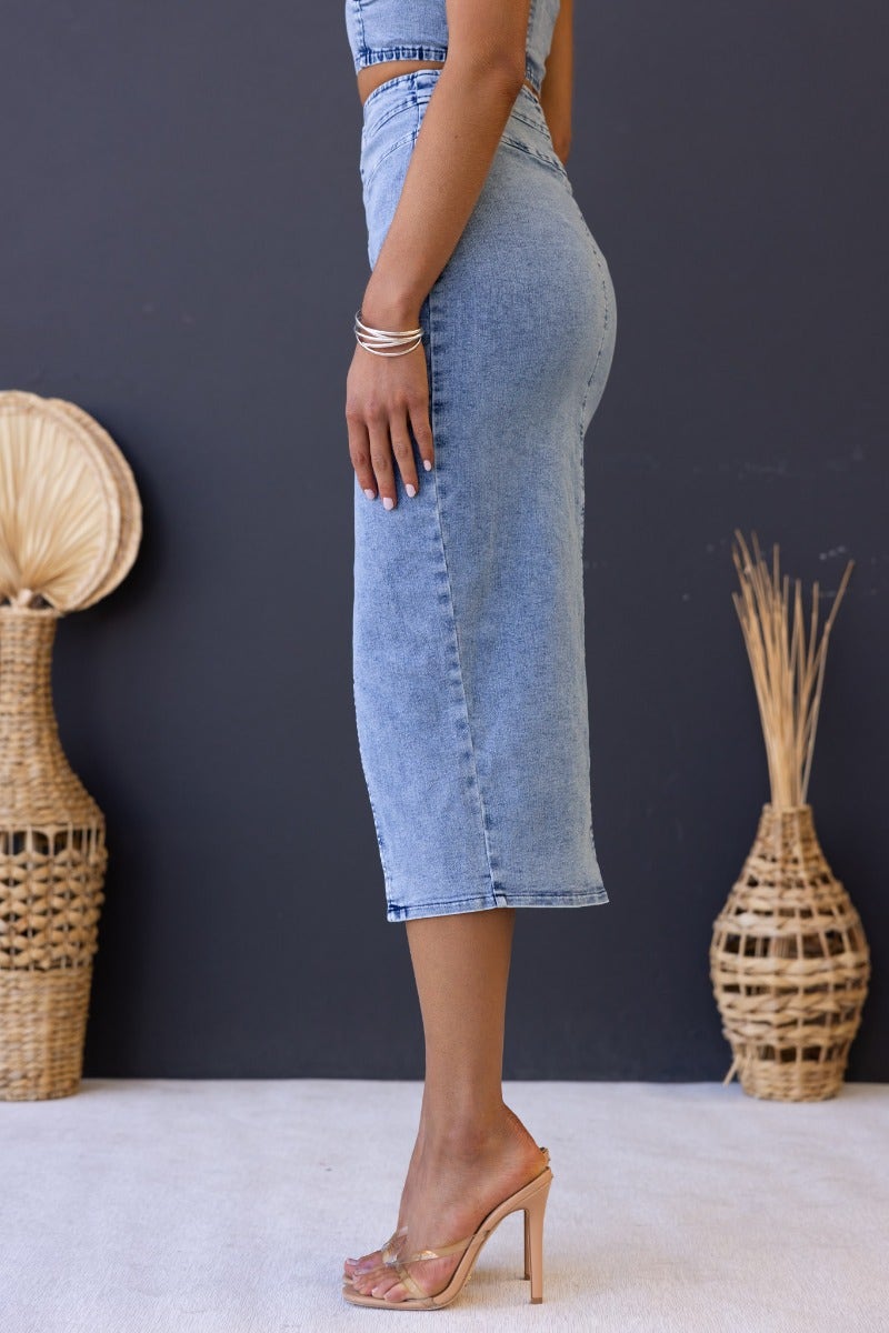 Side view of Genevieve Midi Skirt in light denim; high split, button-up front, fitted silhouette.