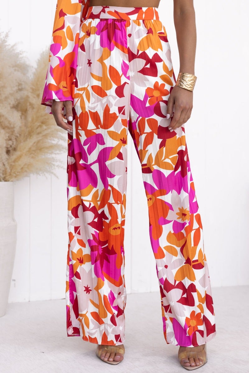 Model wearing the Kira Floral Print Set with wide-leg pants and one-shoulder top featuring vibrant colors and floral design.