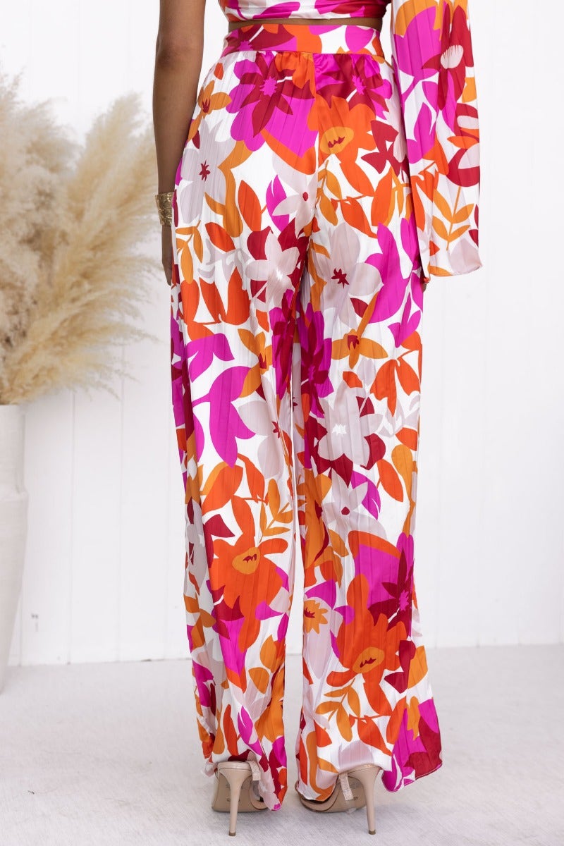 Model wearing Kira Set, a vibrant floral print top and pants with wide sleeves and a twist detail at the bust.