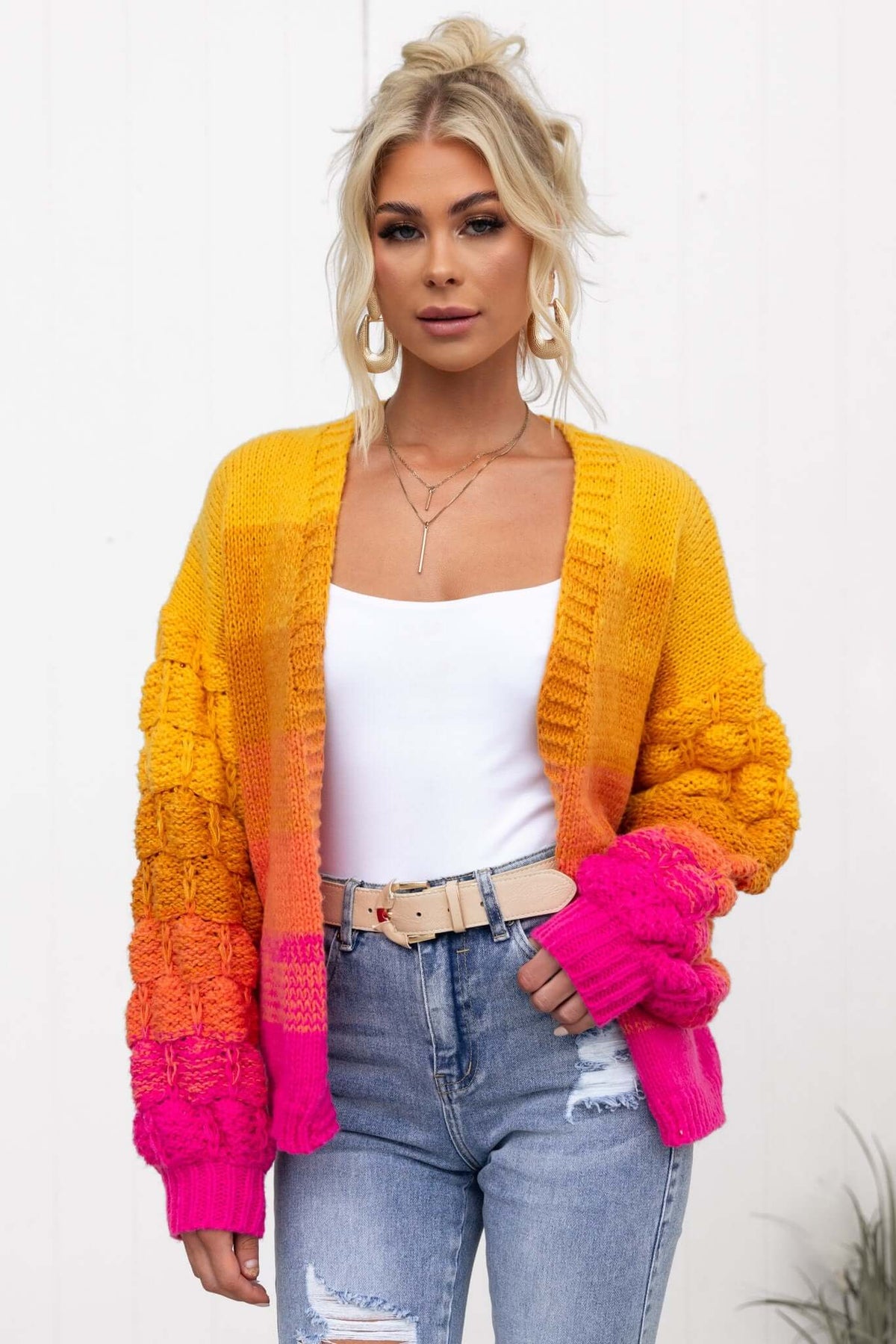 Model wearing Xylia Cardigan in vibrant orange and pink, styled with a white top and denim jeans.