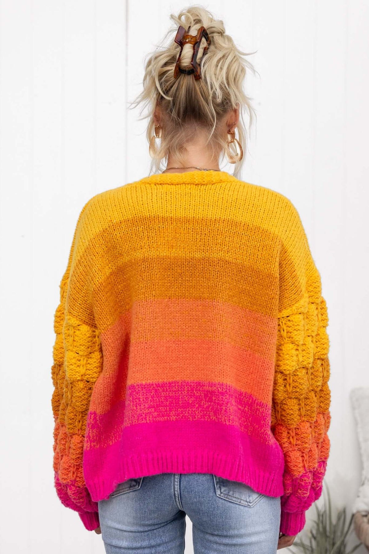Vibrant Xylia cardigan in shades of orange and pink, showcasing a relaxed fit and textured sleeves for a stylish look.