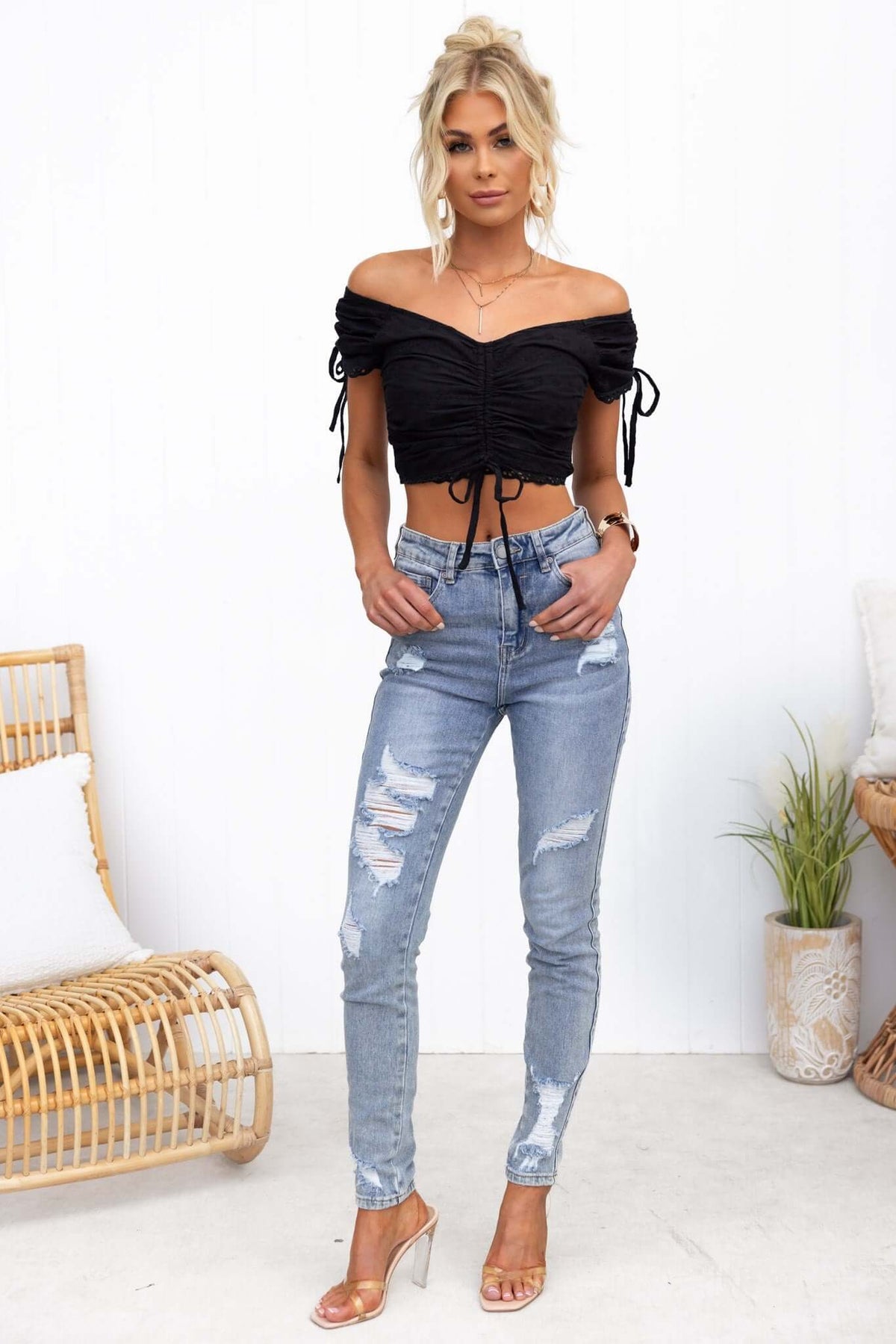 Model wearing a black Hays Top with ruching and tied sleeves, paired with distressed blue jeans.