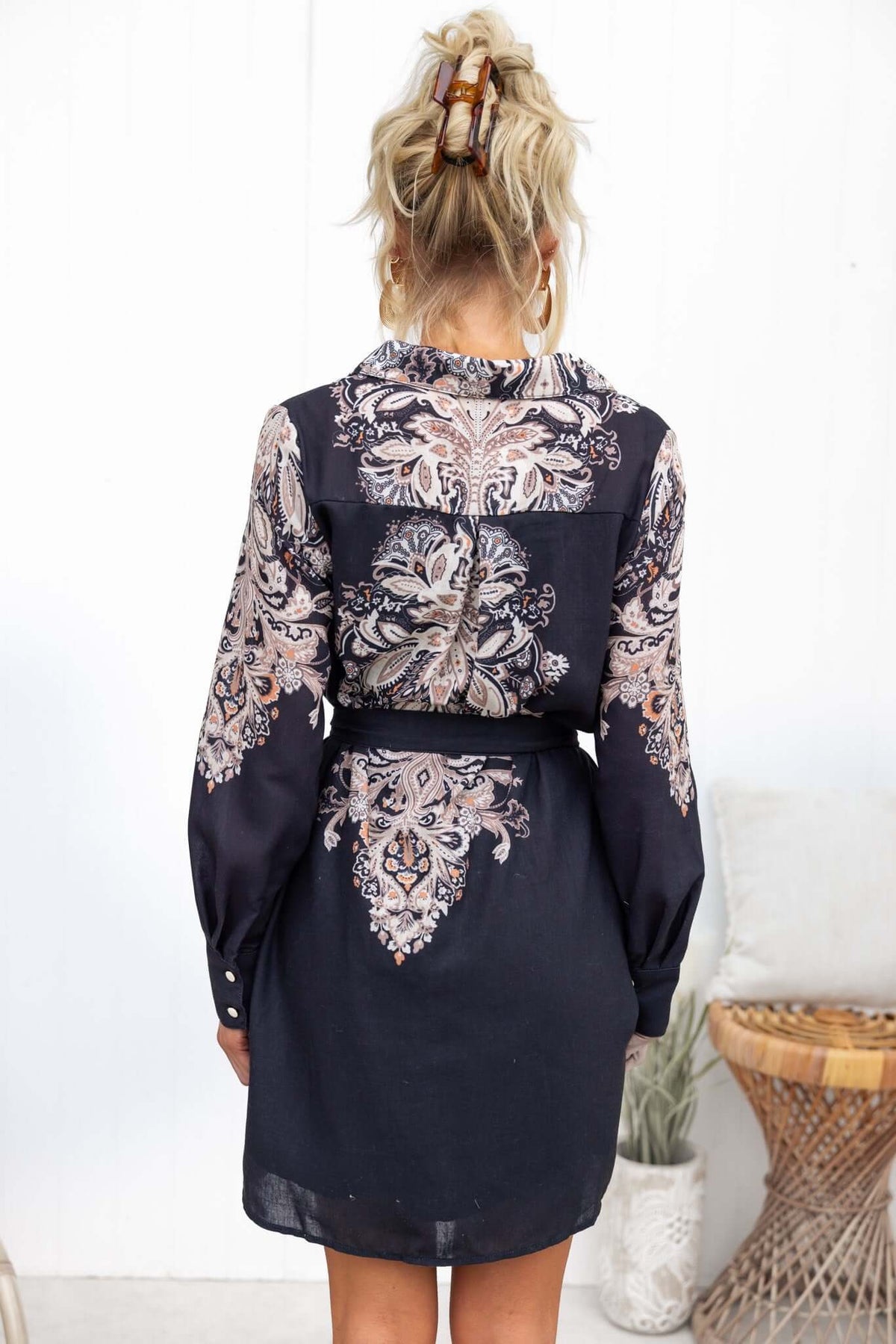 Back view of Channey Dress featuring paisley print, long sleeves, and a removable tie in black with floral details.