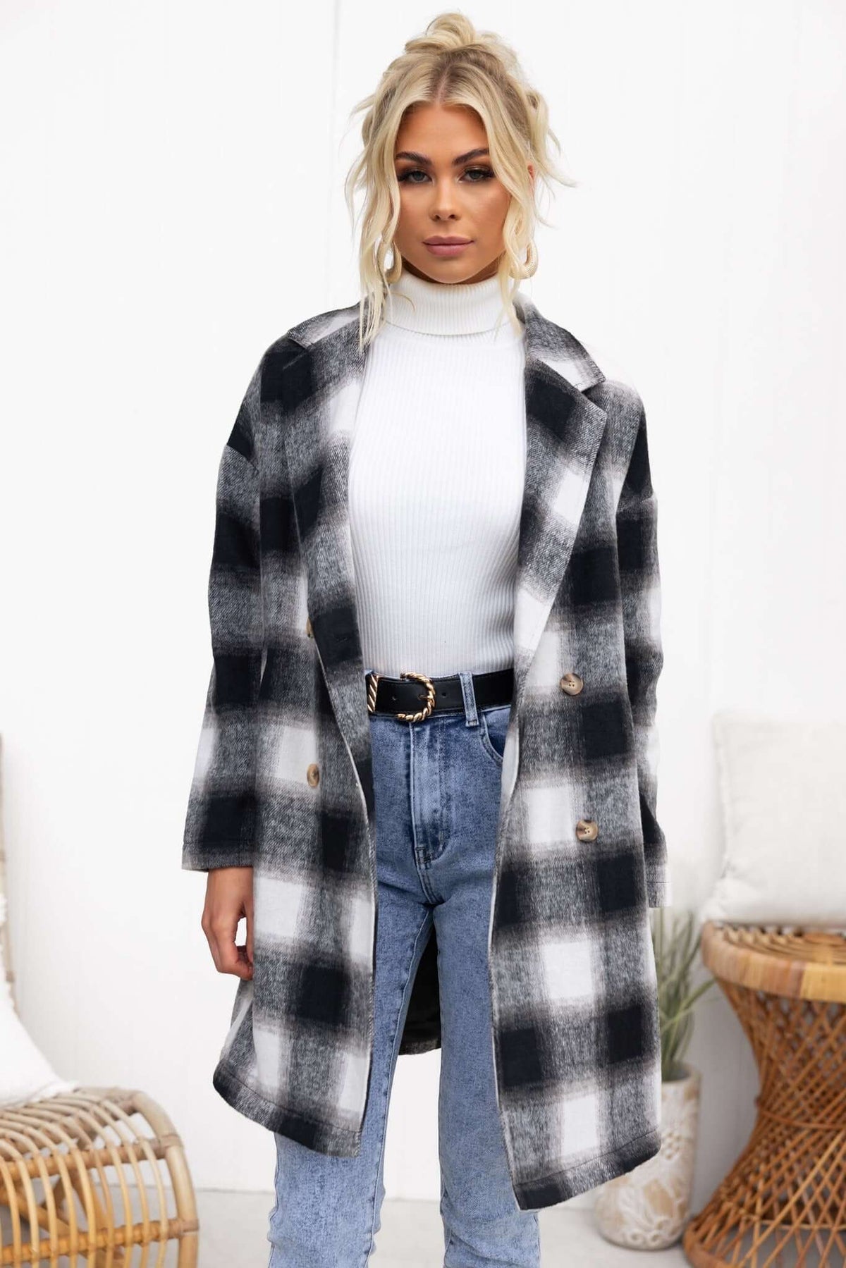 Model wearing a stylish black and white plaid Tiffin coat with a button-up front over a white turtleneck and blue jeans.